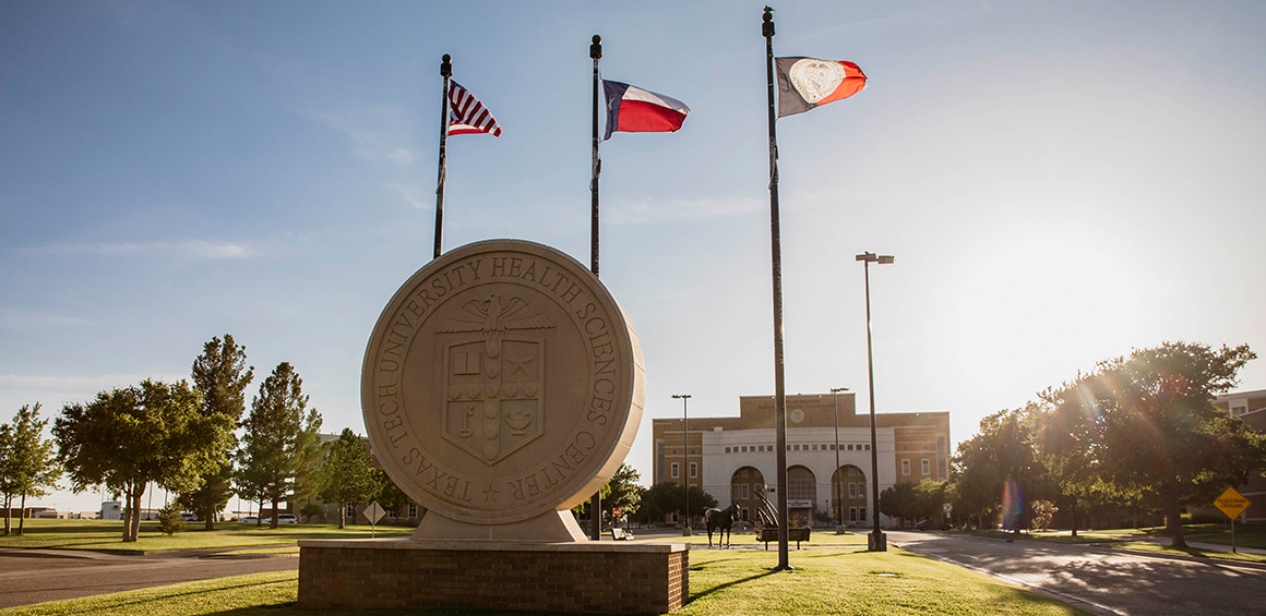 TTUHSC Amarillo campus exterior of front of building and flags out front with the sunsetting