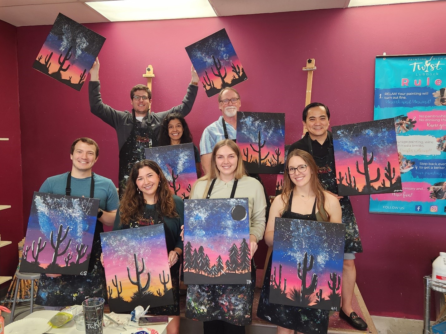 Surgery residents holding up painted cacti canvases in painting room Surgery residents holding up painted cacti canvases in painting room